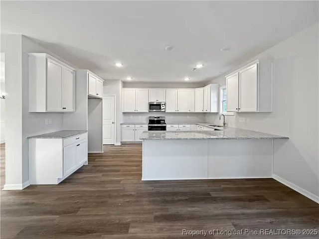 a large white kitchen with wooden floors stainless steel appliances and cabinets