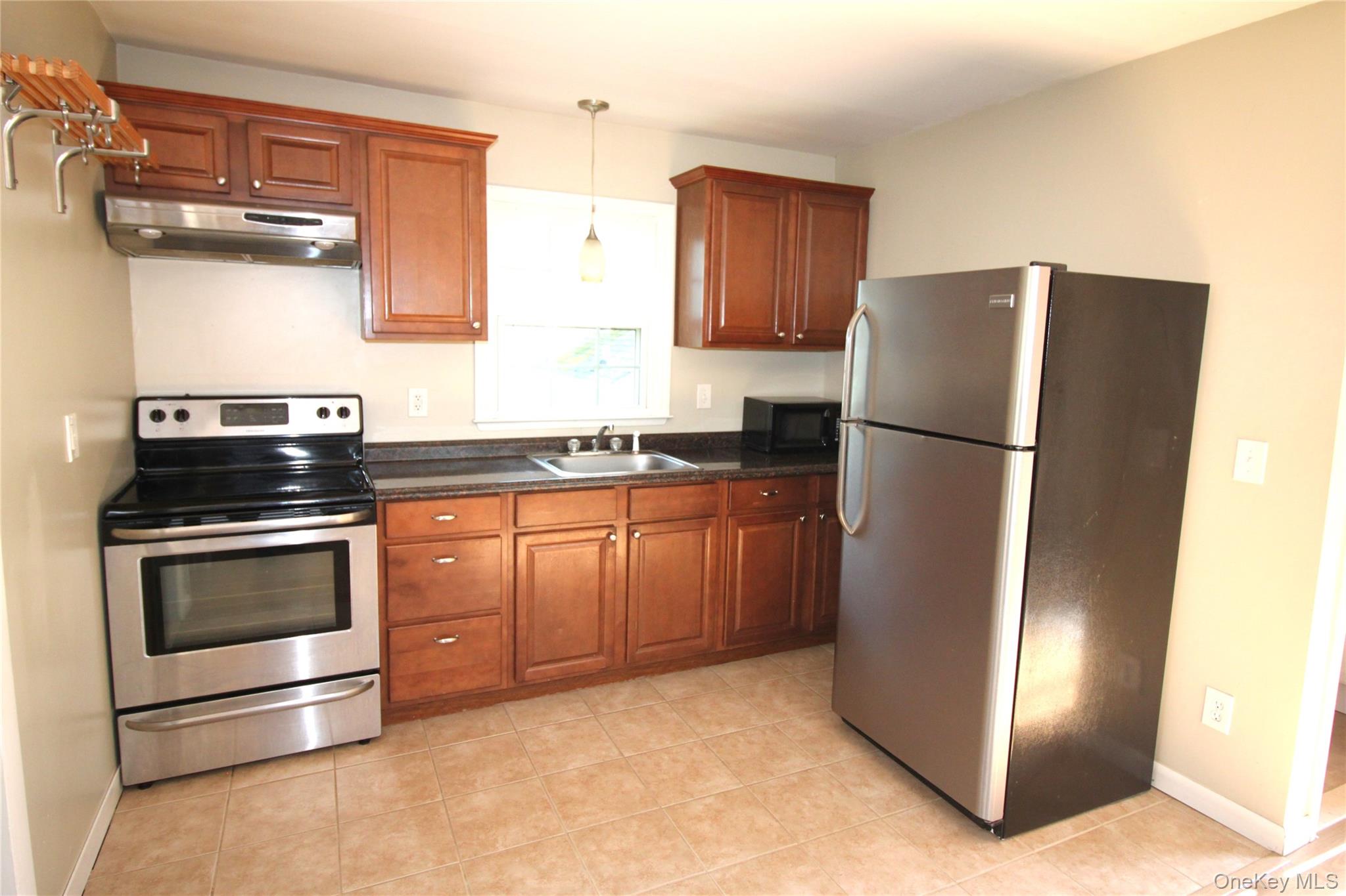 495 Farmers Mills Road Carmel, NY 10512 - Photo 8 of 24 Kitchen featuring dark countertops, a sink, appliances with stainless steel finishes, decorative light fixtures, and under cabinet range hood