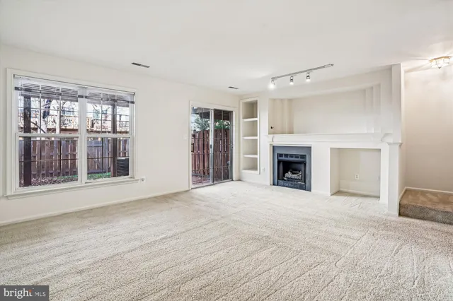 a view of an empty room with a fireplace and a window