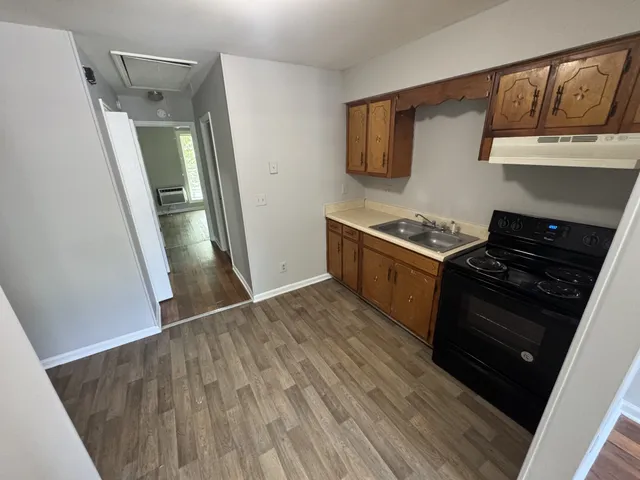 a kitchen with a stove and a wooden floor