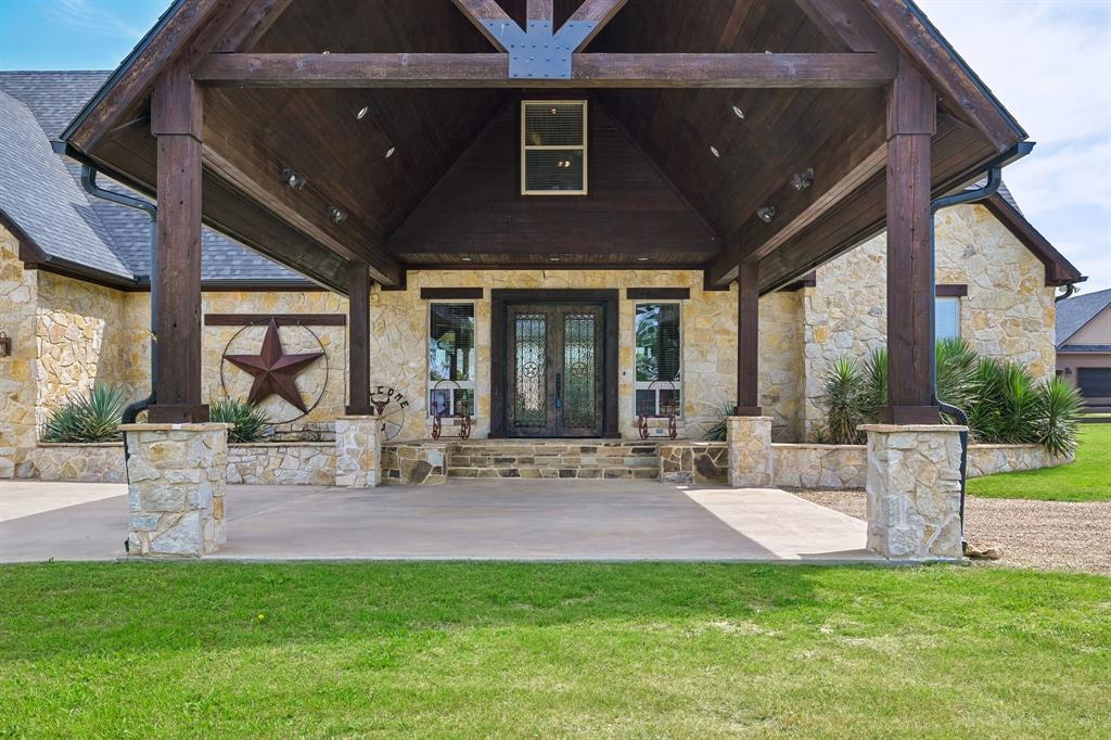 2085 Switzer Road Sanger, TX 76266 - Photo 5 of 39 Stone facade entry with a prominent covered portico featuring dark wood beams and columns