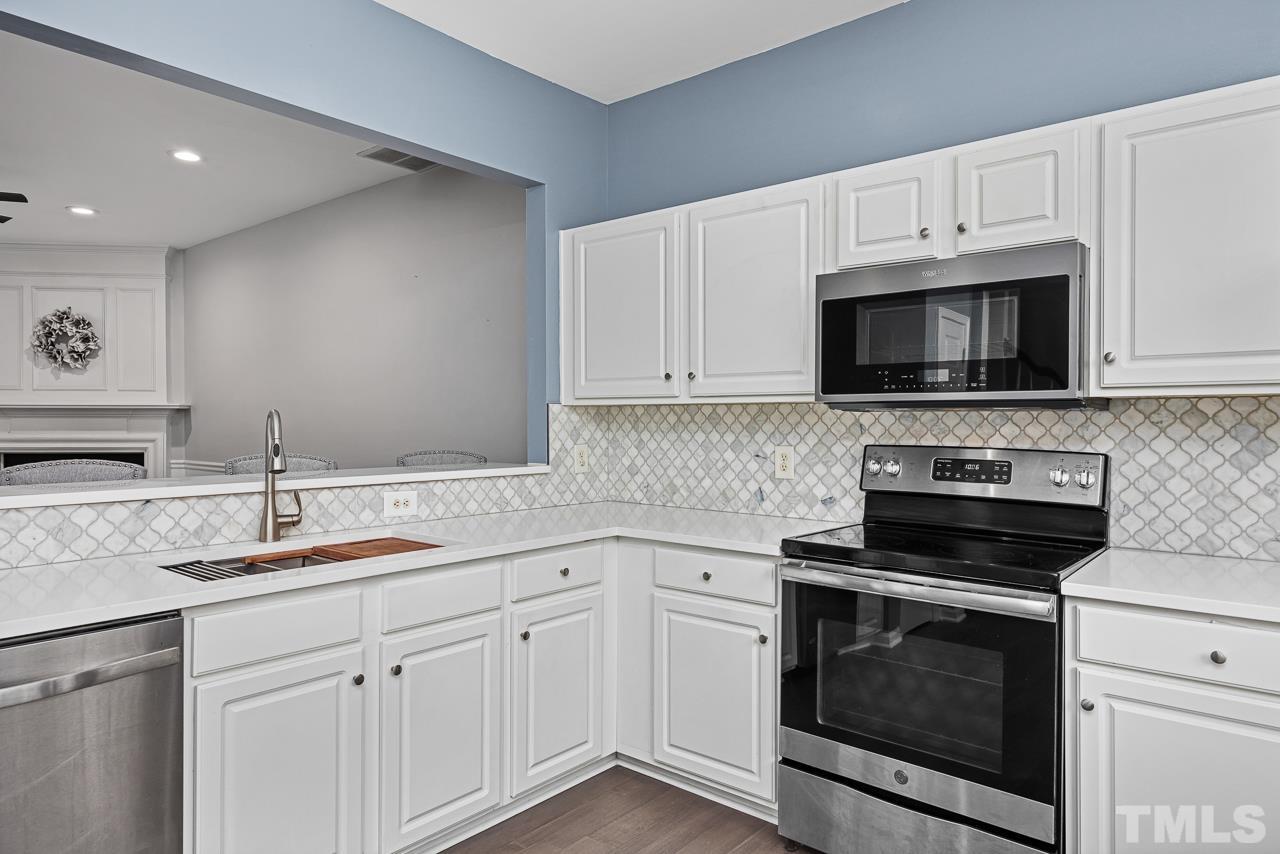 4422 Vienna Crest Drive Raleigh, NC 27613 - Photo 6 of 28 a kitchen with white cabinets and stainless steel appliances