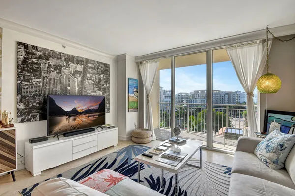 a living room with furniture a flat screen tv and a floor to ceiling window