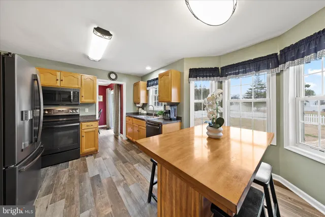 a kitchen with stainless steel appliances granite countertop a refrigerator a stove and a dining table with wooden floor