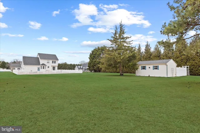 a view of a big house with a big yard and large trees