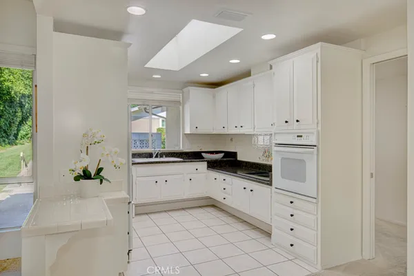 a kitchen with white cabinets and window