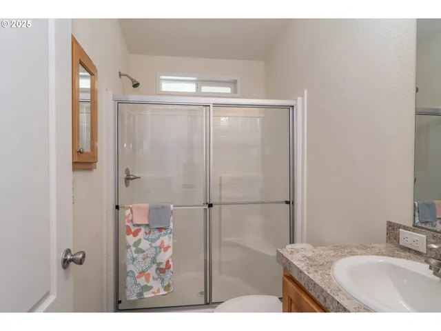 a bathroom with a granite countertop sink a mirror and shower