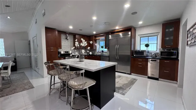 a kitchen with stainless steel appliances kitchen island granite countertop a table chairs sink and cabinets