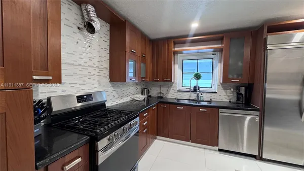 a kitchen with stainless steel appliances granite countertop a sink stove and refrigerator