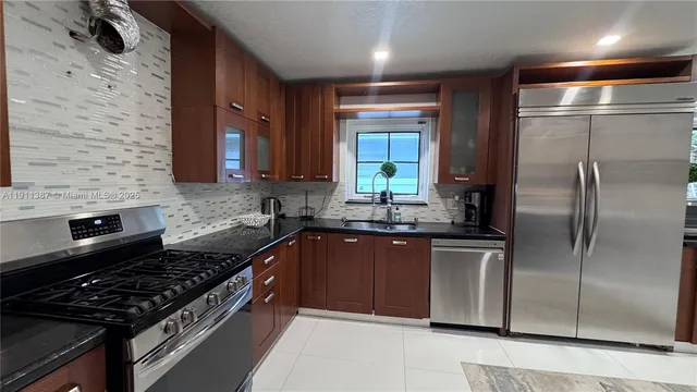a kitchen with stainless steel appliances granite countertop a refrigerator and a sink
