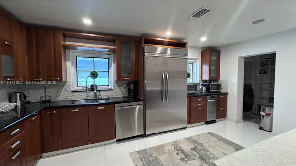 a kitchen with stainless steel appliances kitchen island granite countertop a refrigerator and a sink