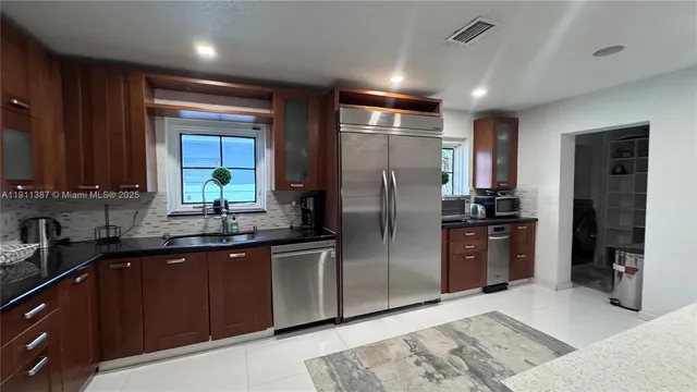 a kitchen with stainless steel appliances kitchen island granite countertop a refrigerator and a sink