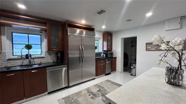 a kitchen with stainless steel appliances kitchen island granite countertop a refrigerator and a sink