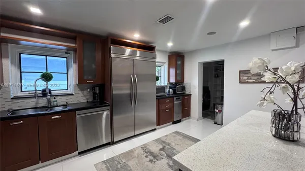 a kitchen with stainless steel appliances kitchen island granite countertop a refrigerator and a sink