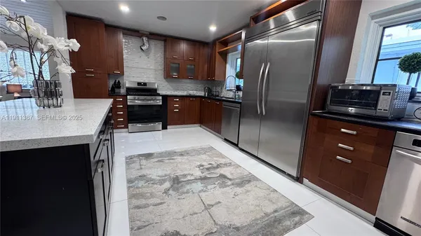 a kitchen with stainless steel appliances granite countertop a sink a stove and a refrigerator