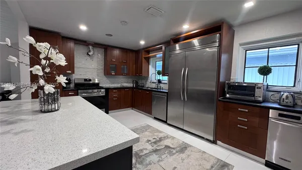 a kitchen with stainless steel appliances granite countertop a sink a stove and a refrigerator