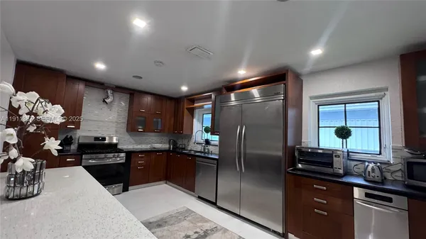 a kitchen with stainless steel appliances kitchen island granite countertop a refrigerator and a sink