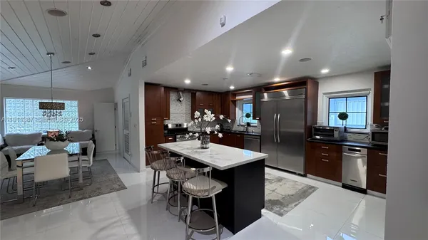 a large white kitchen with lots of counter space a sink and appliances