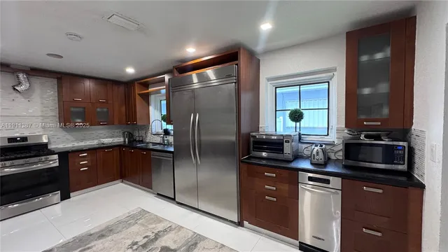 a kitchen with stainless steel appliances granite countertop a sink refrigerator and cabinets