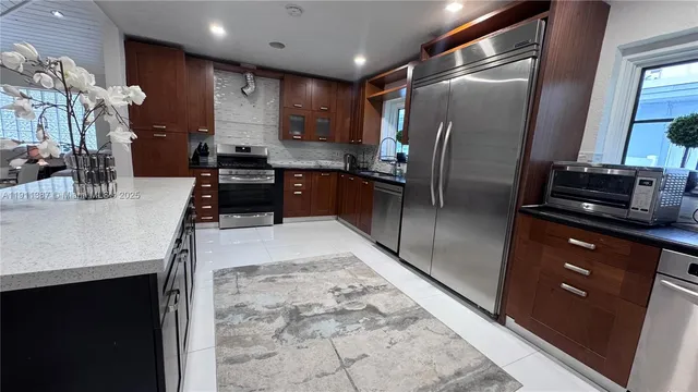 a kitchen with stainless steel appliances granite countertop a refrigerator a sink a stove and island