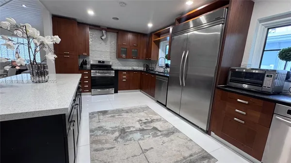 a kitchen with stainless steel appliances granite countertop a refrigerator a sink a stove and island