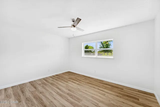 an empty room with a window and ceiling fan