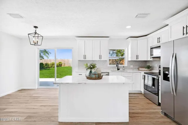 a kitchen with stainless steel appliances kitchen island granite countertop a refrigerator a stove and a sink