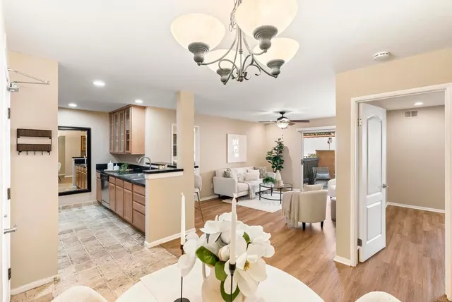 a large kitchen with a refrigerator a stove a sink dishwasher a dining table and chairs with wooden floor