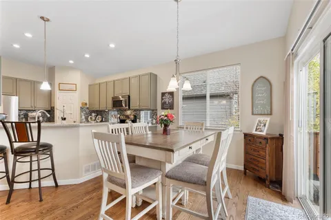 a dining room with stainless steel appliances kitchen island granite countertop a table chairs and a view of living room