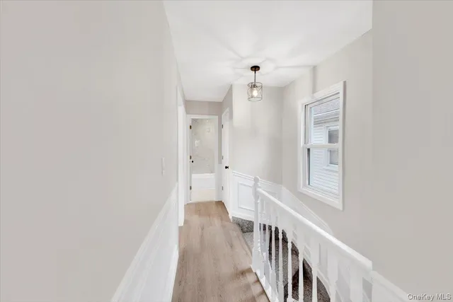 a view of a hallway with wooden floor and a bathroom