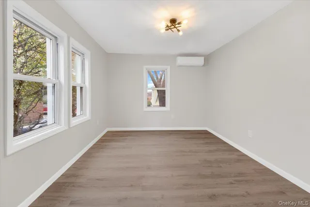 a view of an empty room with a window and wooden floor
