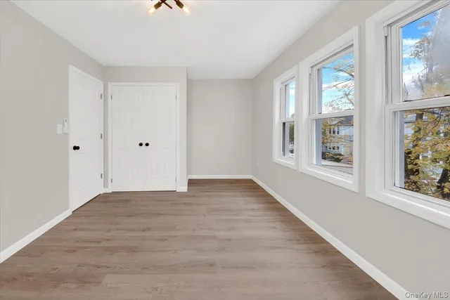 a view of an empty room with window and wooden floor