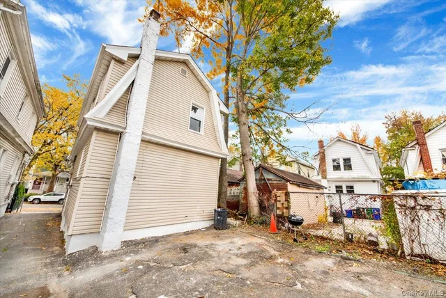 a view of a white house with a large tree and wooden fence