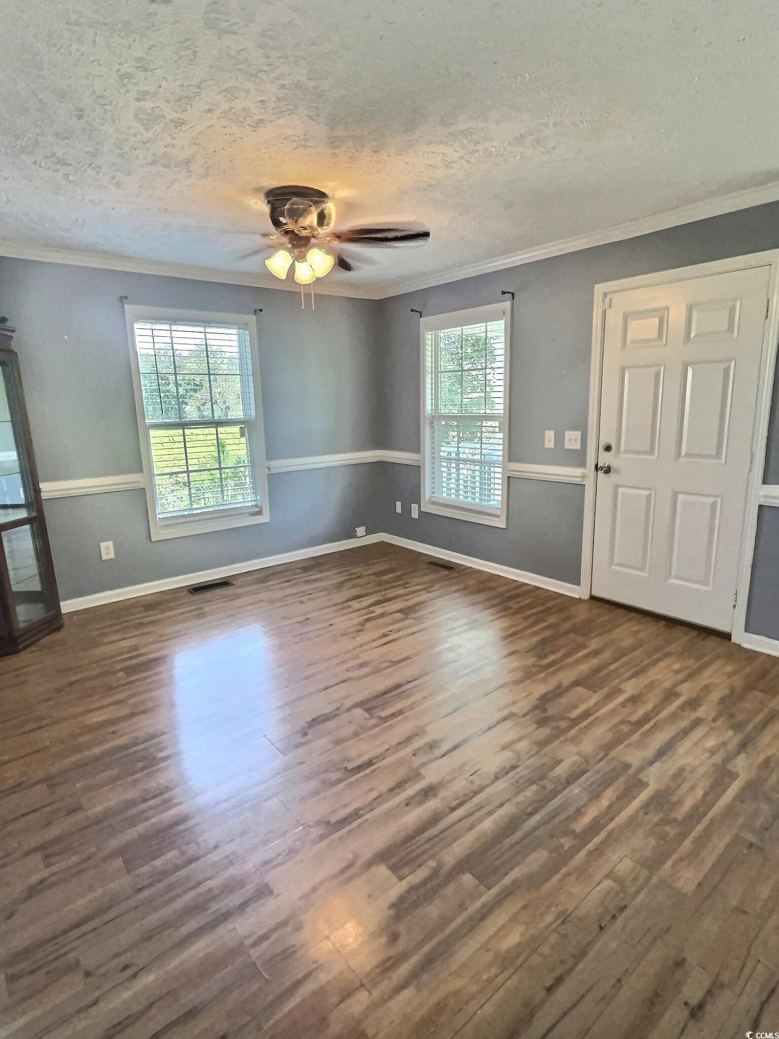 1000 Westgate Place Loris, SC 29569 - Photo 9 of 26 Unfurnished living room featuring ornamental molding, a textured ceiling, dark wood-type flooring, and a ceiling fan