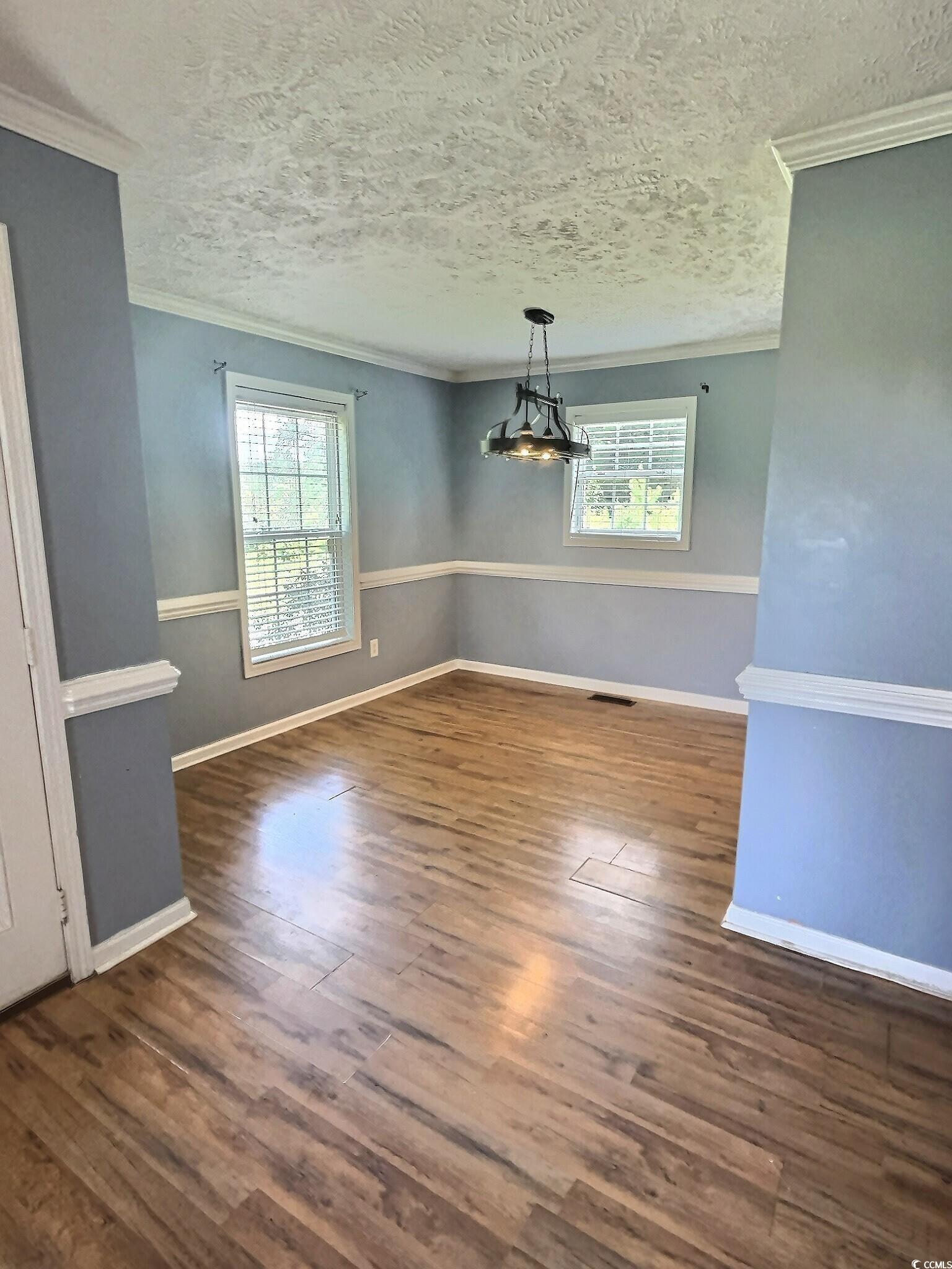1000 Westgate Place Loris, SC 29569 - Photo 10 of 26 Unfurnished dining area with ornamental molding, plenty of natural light, a textured ceiling, and dark wood finished floors