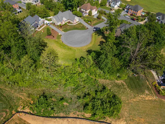 an aerial view of residential house with outdoor space and trees all around
