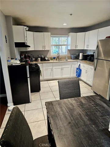 a kitchen with stainless steel appliances kitchen island granite countertop a refrigerator a stove a sink and white cabinets