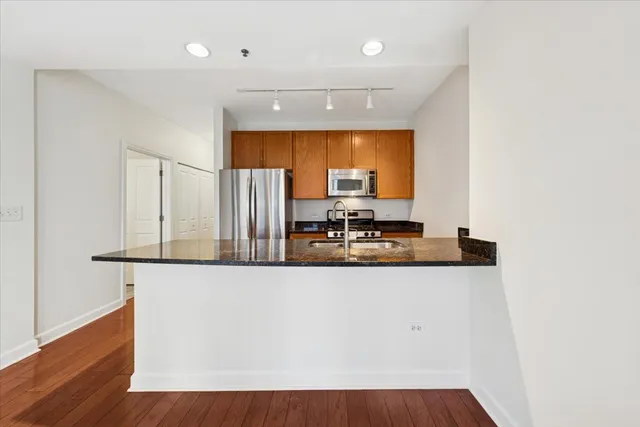 a view of a kitchen with kitchen island a sink wooden floor and counter top space