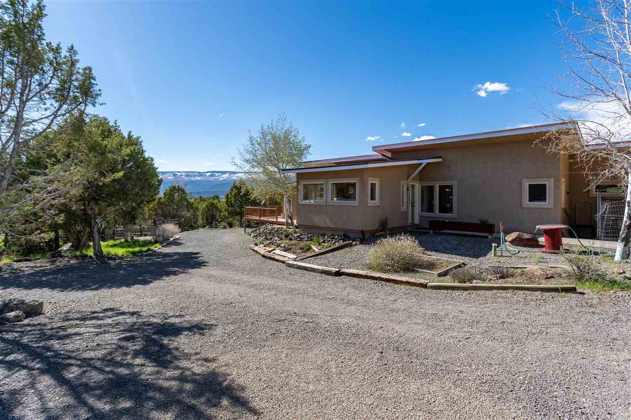 18735 Northridge Road Cedaredge, CO 81413 - Photo 3 of 26 a view of a house with large trees and wooden fence