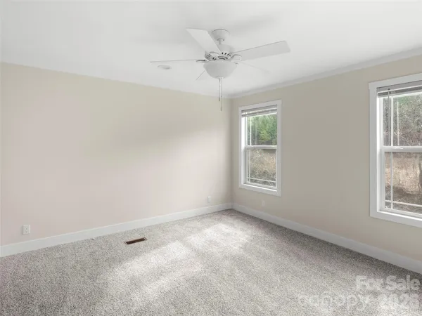 an empty room with windows and fan
