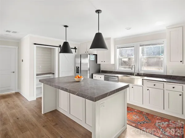a kitchen with stainless steel appliances granite countertop a sink a window and chairs