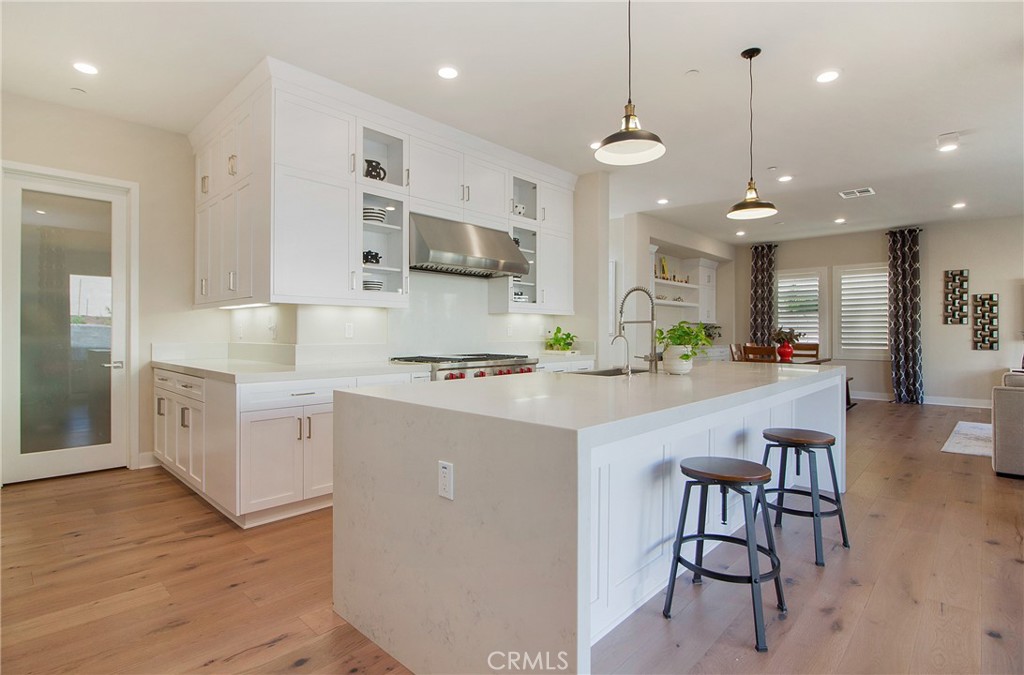 57 Sagan Way Irvine, CA 92618 - Photo 9 of 40 a kitchen with stainless steel appliances kitchen island granite countertop a stove a sink a refrigerator and white cabinets with wooden floor