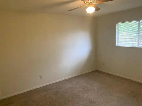 an empty room with a window and a fan