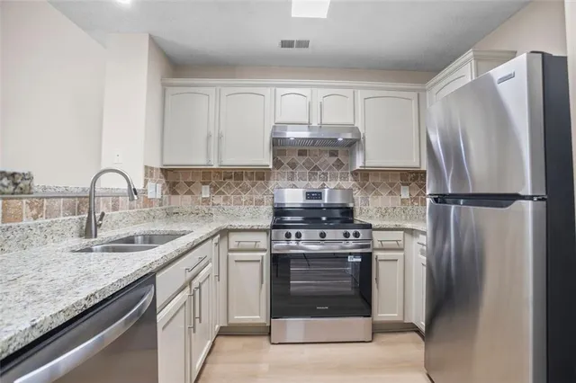 a kitchen with stainless steel appliances granite countertop a sink stove and refrigerator