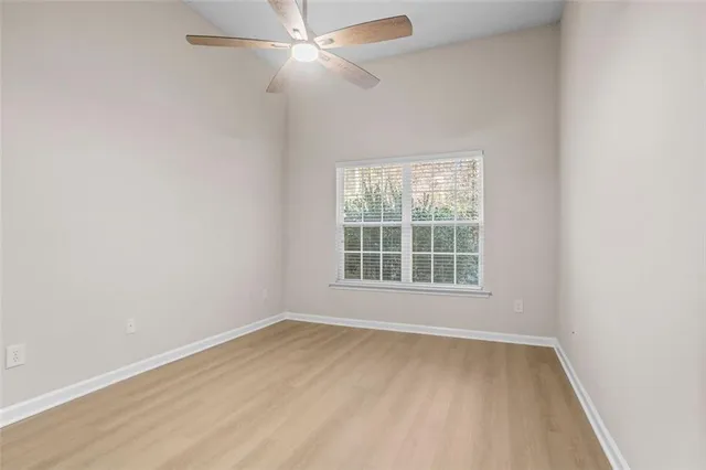 an empty room with a window and ceiling fan