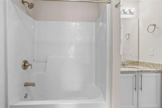 a bathroom with a granite countertop sink a mirror and a bathtub