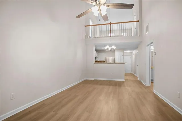 an empty room with wooden floor chandelier and windows