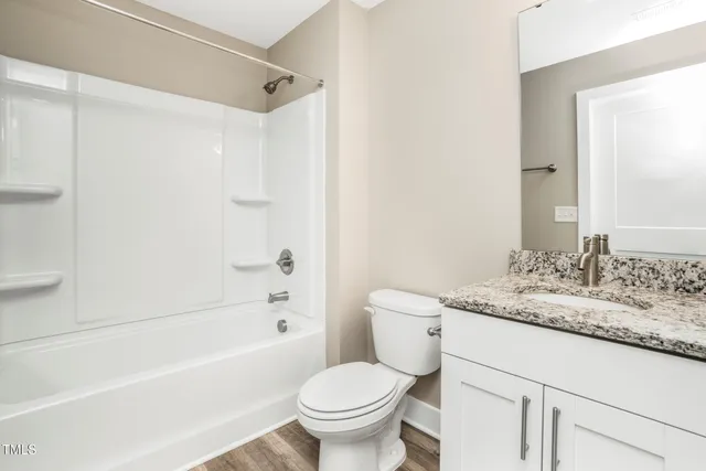 a bathroom with a granite countertop toilet a sink and a bathtub