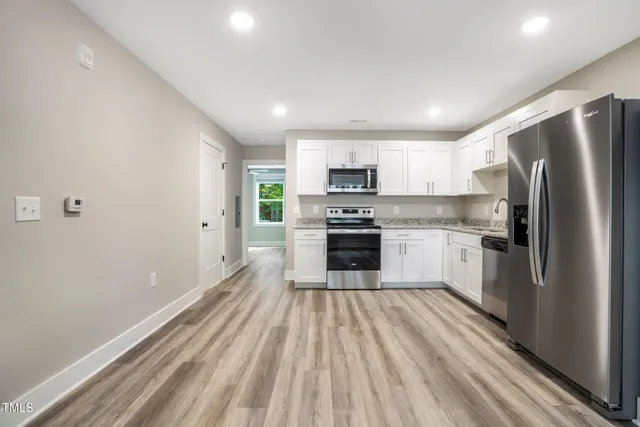 a kitchen with kitchen island white cabinets stainless steel appliances and a refrigerator