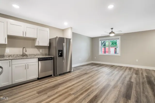 a kitchen with granite countertop a refrigerator sink and cabinets